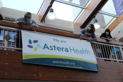 Astera Health staff members draped a large banner over the courtyard banister announcing the official name change to Astera Health.