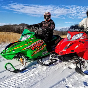 Red snowmobile and green snowmobile