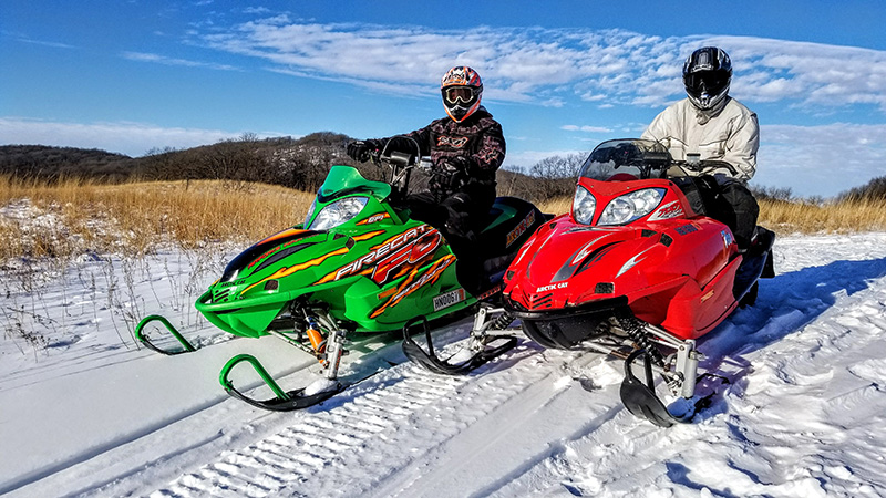 Red snowmobile and green snowmobile